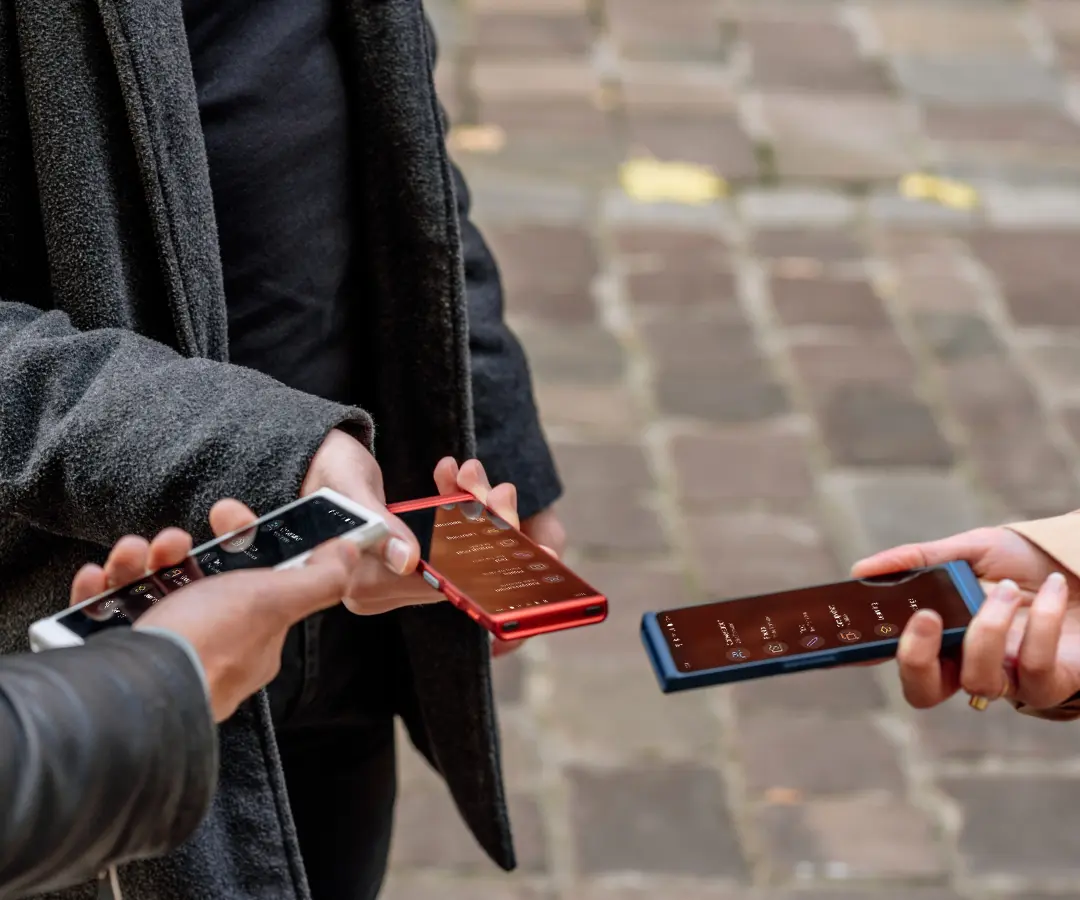 Tre amiche che tengono felicemente in braccio i loro traduttori, impegnate in conversazioni e momenti di condivisione insieme. 