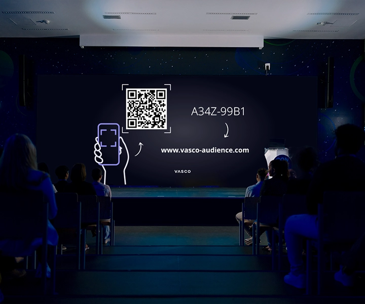Un grande schermo nella sala conferenze mostra le istruzioni "Join Vasco Audience" (Unisciti a Vasco Audience), fornendo ai partecipanti indicazioni su come accedere alla sessione.