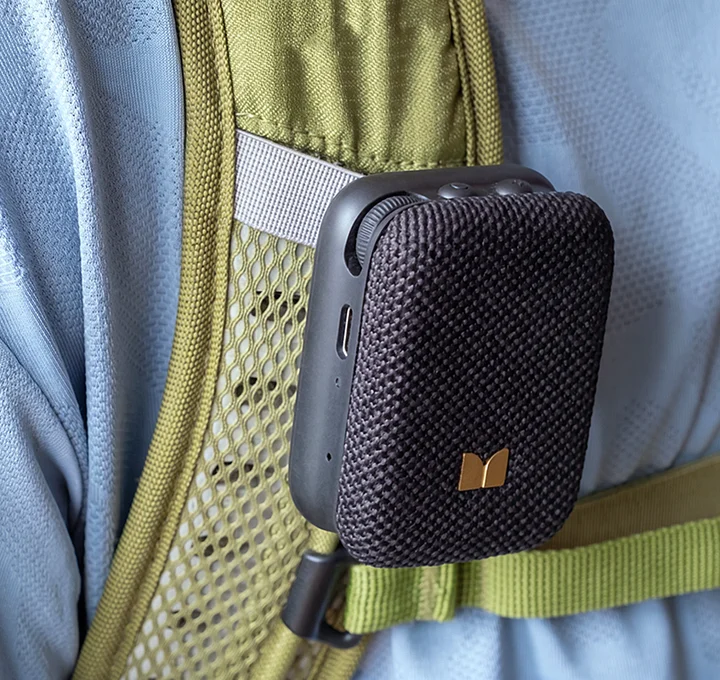 Mini altoparlante Bluetooth nero agganciato al cinturino verde oliva di uno zaino